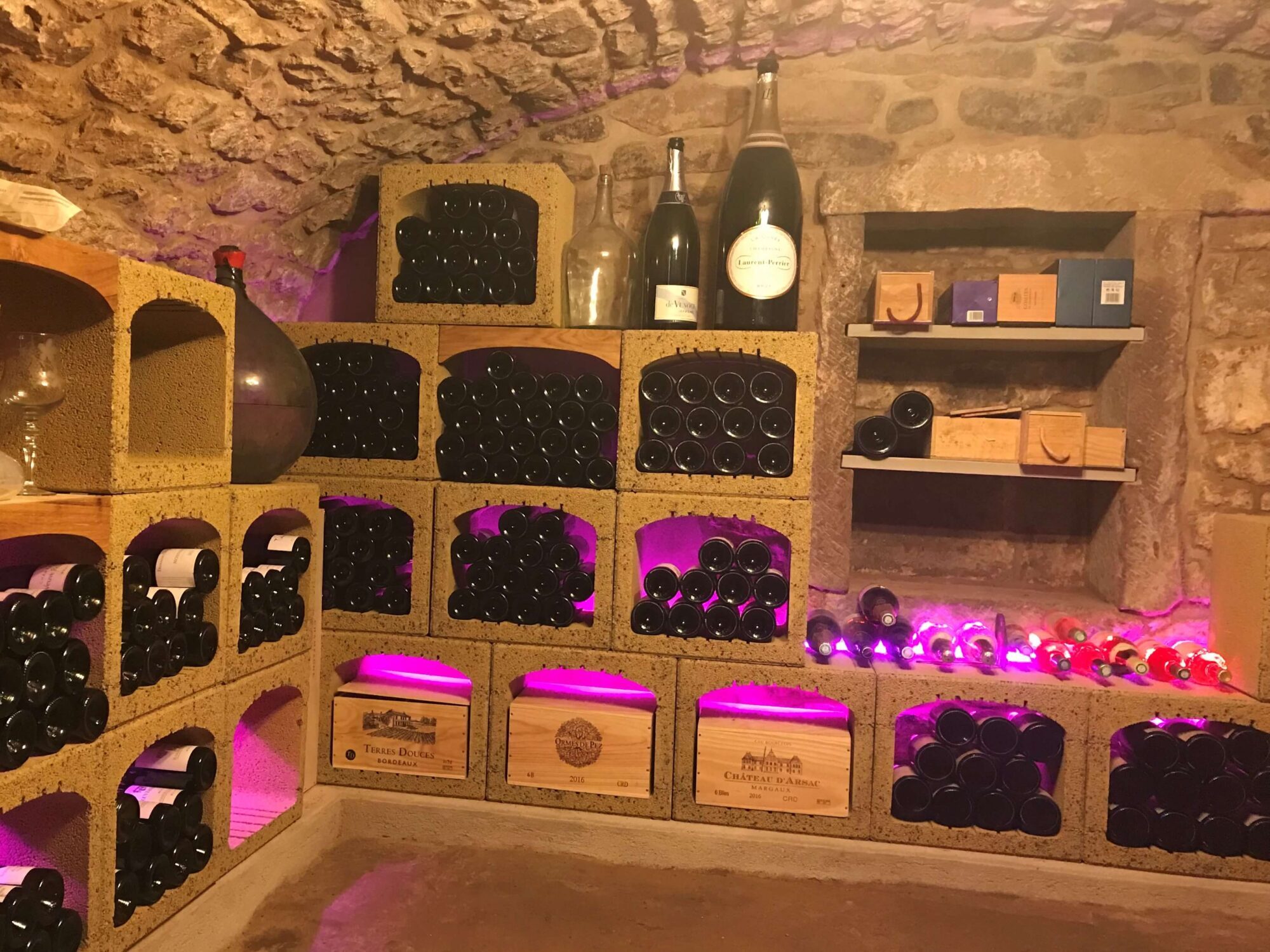 Cave à vin voûtée et enterrée. Aménagement avec le casier à vin en pierre et argile rouge Vinobloc.
