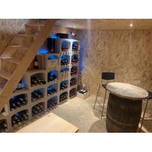 casier à bouteille de vin en pierre sous un escalier en bois